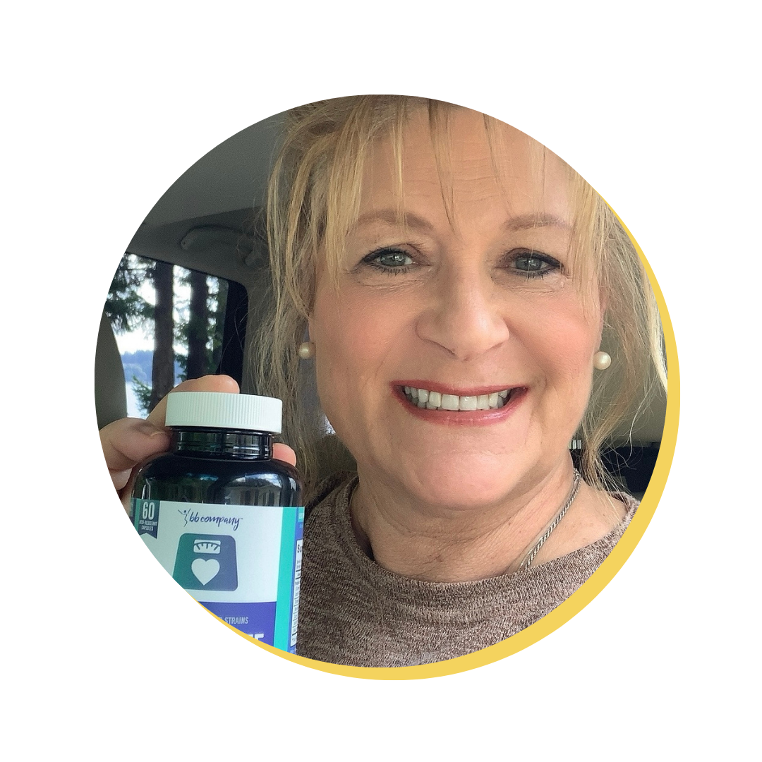 Person smiling and holding a bottle of vitamins in a car.